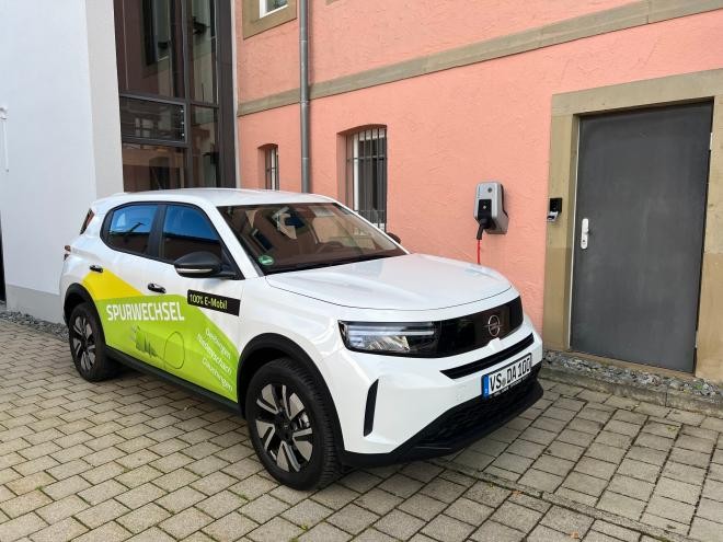 Der neue Opel Frontera geparkt am Hintereingang des Rathauses. Auf dem weißen Auto steht in grün- und gelb Spurwechsel.