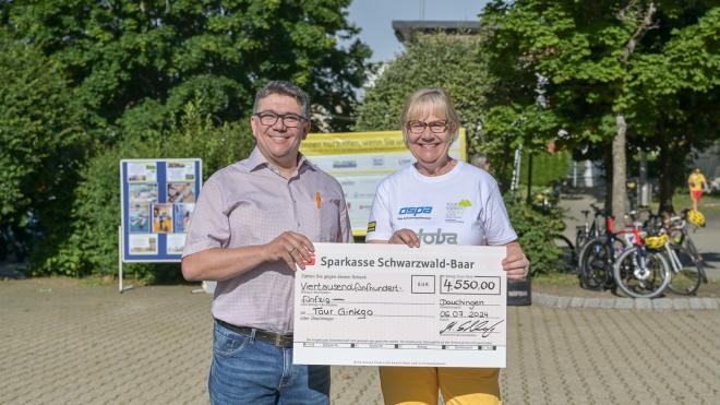 Bürgermeisterstellvertreter Schleicher links hält in einer Hand den Scheck und rechts daneben die Initiatorin der Tour Ginkgo Christiane Eichendorfer sie hält ebenfalls in einer Hand den Scheck.